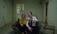 En man och en kvinna sitter i en stor fåtölj, mannen häller upp öl ur en flaska i kvinnans glas.